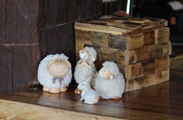 Statue of three teddy sheeps and a rabbit dolls on the wooden table.