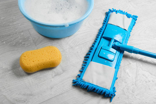 Mopping, blue wet microfiber mop with detergent. Cleaning disinfection kit on a white floor isolated. Housekeeping concept