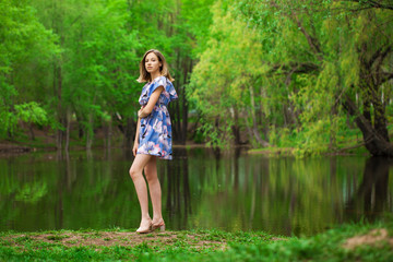 Fototapeta na wymiar Portrait of a young beautiful woman in blue dress posing by the lake