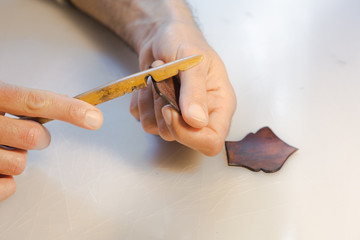 Leather edge burnishing, leather edge finishing by handmade tools. The process of manufacturing a leather wallet handmade. The artisan sewes a leather wallet.