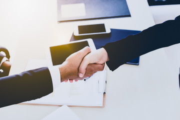 Business partners handshake over office table during negotiation and meeting. Business people introduce themselves, welcome colleagues, congratulate with successful deal. Top view shake hands of deal