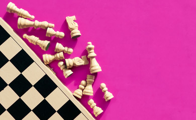 White chess pieces lying next to a chessboard, top view.