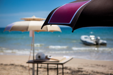 ombrelloni aperti e sullo sfondo mare  e cielo  blu e un motoscafo pronto a partire