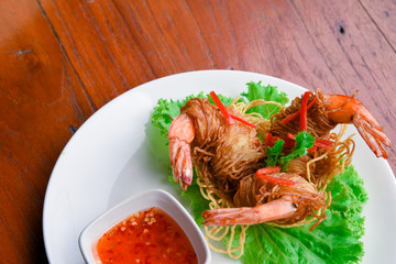 Goong Sarong  noodles Wrapped Shrimp With Crispy Noodle Serve, vegetable and sauce in white plate  on wood table , Thai food