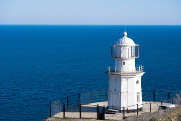 Fototapeta na wymiar White Lighthouse against the blue sea. 