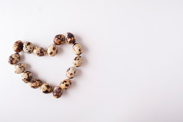 Quail eggs are isolated on a white background. Shape of heart from the quail of eggs with copy space. Top view