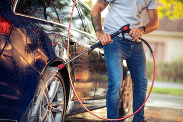 Man washing his car with pressure washer