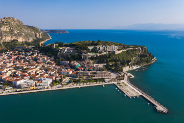 Green peninsula with Nafplion city in Greece from above with blue Mediterranean sea, old town roofs and small port