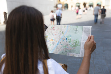 Young woman looking a map and some handwritten notes on it to get to the best city attractions.