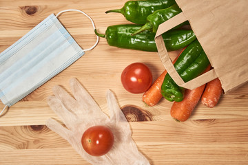 Some vegetables inside a paper bag and supplies against coronavirus
