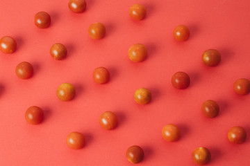 Colorful pattern of cherry tomatoes on red background. Top view