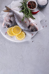 Delicious raw dorado or sea bream fish with lemon spices, fresh rosemary on marble board view from above