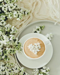 Composition with the branches of lilac and fresh coffee with foam in white cup. Relax time, pay yourself first/