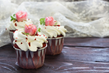Red velvet cupcakes with wipped cream and pink rose flowers