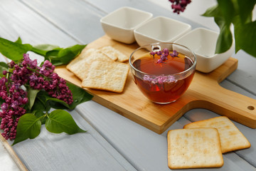 Cup Of Tea, Lilac Flowers and cracker on a Wooden Background