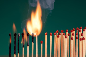 Concept of stopping the infection and contagion of pandemics and virus epidemics. Social distancing. Matches in a row burning for domino effect.