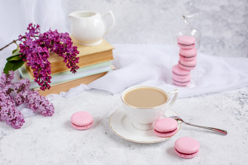 Fototapeta na wymiar postcard good morning. a Cup of coffee , a branch of lilac, macaroons, old books .