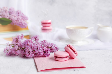 Fototapeta na wymiar postcard good morning. a Cup of coffee , a branch of lilac, macaroons, old books .