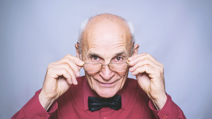 portrait of elderly old man holding glasses with hands