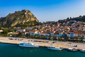 Green peninsula with Nafplion city in Greece from above with blue Mediterranean sea, old town roofs and small port