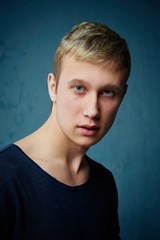 Handsome young man in stylish clothes posing against studio background. portrait of a young man with blond hair and blue eyes.