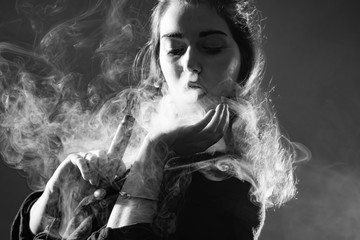 Vaping. Black-and-white portrait of a girl with a VAPE. A female Vaper. The concept of Smoking electronic cigarettes. VAPE shop.