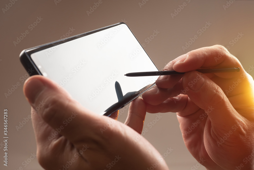Poster smartphone and stylus close-up. a person is holding a smartphone and a stylus. touch screen. the dev