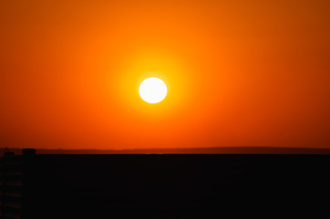 The disc of the sun in orange sky at sunset golden hour