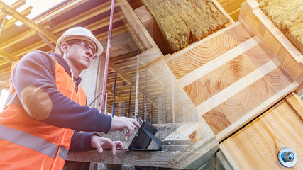 Construction materials for a new house. Engineer with a tablet on a construction site. A man in a...
