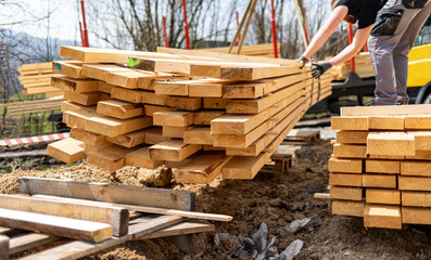 Unloading wooden beams from truck on construction site  for building a house