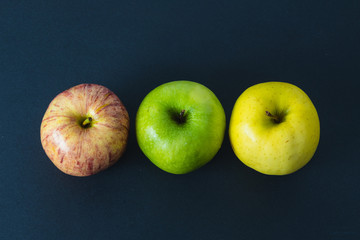 3 different colors of apples on black background. Top view