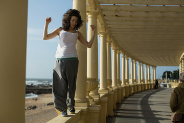 Mixed-race asian woman walks along the railing of ocean promenade. Porto, Portugal.