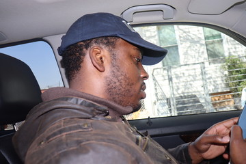 Man sitting in parked car dialing on cell phone