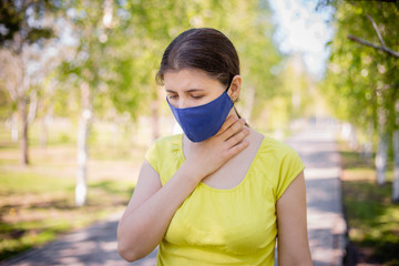 The girl in the mask holds his hand by the throat. Concept of sore throat and lack of fresh air...