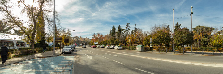Toledo, Spain - Dec 17, 2018: The Cardenal Tavera Street in the direction to the Puerta Nueva de Bisagra. On the right - Park La Vega in Toledo city, Spain, Europe. Wide angle panorama