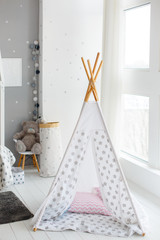 Kid's wigwam in children room. Unisex gender neutral room. DIY children house. Do it yourself textile toy house for kids. Stylish modern children room in scandy style. Cute Handmade Teepee In A Room.