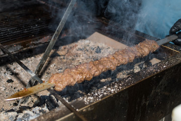 Chef preparing meat on the grill, during outdoor outside food festival