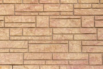 Vintage stone brick wall texture background with pinkish tan color textured surface, showing minor cracks and weathering from age