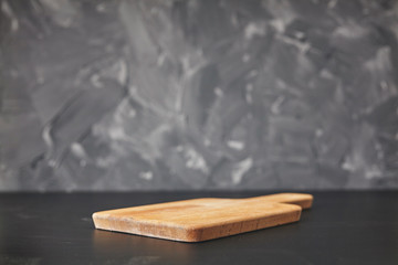 Cooking background with empty wooden cutting board on gray