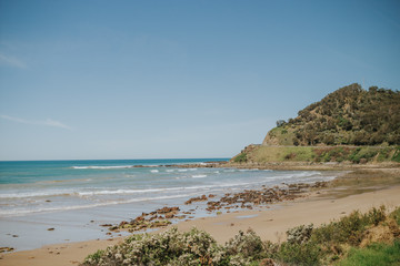 Blue water ocean , white sand, and mountains in the background.