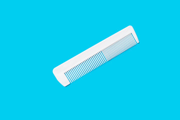 white simple plastic comb on a blue background