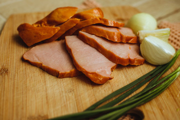 The meat is cut on a wooden Board. Fast food. Breakfast.Picnic in nature.Natural smoked meat.