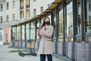A brunette girl with long hair in a navy blue face mask to avoid the spread coronavirus uses a...