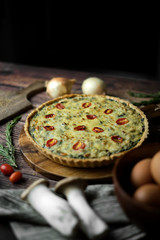 Homemade cheesy spinach quiche for brunch. set on wooden cafe table background.