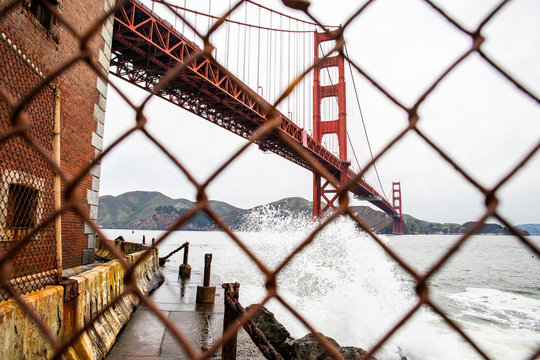 A rusted chain link fence in front of the Golden Gate Bridge.