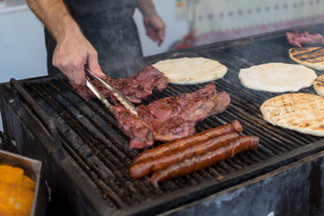 Chef preparing meat on the grill, during outdoor outside food festival