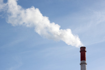 Production chimney with white smoke against a blue sky with white clouds. The concept of ecology, the ozone layer.
