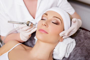 cosmetology and beauty concept - woman getting facial anti-aging procedure in beauty salon