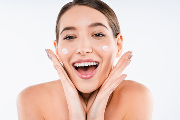 Happy caucasian young woman applying cream on her skin isolated on white background