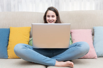 a girl sitting on a couch with a laptop resting on her legs